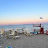 Spiaggia con lettini, ombrelloni chiusi e torre di salvataggio.