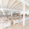 Sala da pranzo ampia con tavoli apparecchiati e sedie bianche.