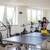Sala fitness con attrezzature e tavolo da ping pong, persona in piedi.