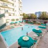 Piscina all'aperto con ombrelloni verdi e persone che nuotano.