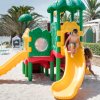 Bambini giocano su uno scivolo colorato su una spiaggia.