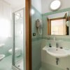 Bagno luminoso con doccia, lavabo e WC. Piastrelle color menta e specchio sopra il lavabo.
