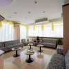 Sala d'attesa con divani colorati, tavolini e finestre luminose. Due persone sedute.