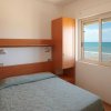 Camera da letto con finestra vista mare, letto matrimoniale e mobili in legno chiaro.