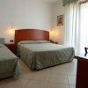 Stanza con letto matrimoniale e singolo, arredamento semplice e porte finestre.