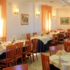 Ristorante elegante con tavoli apparecchiati, sedie in legno e tende arancioni.