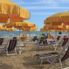 Spiaggia con ombrelloni gialli e lettini blu a righe sotto un cielo sereno.