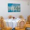 Tavolo rotondo apparecchiato con sedie intrecciate, quadro nautico sul muro.