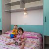 Due bambini giocano su un letto a righe colorate.