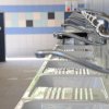 Fila di rubinetti sopra lavandini in un bagno pubblico con piastrelle a motivi chiari e scuri.