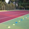 Campo da tennis rosso e verde con coni colorati lungo il bordo.