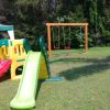 Un parco con uno scivolo colorato, altalene e un gazebo su prato.