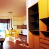 Cucina luminosa con tavolo giallo, sedie, divano a fantasia e credenza in legno.