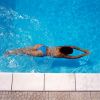 Persona nuota in una piscina blu, vista dall'alto.