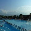 Piscina all'aperto con scivoli e persone che nuotano.