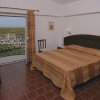 Una camera con letto matrimoniale, pavimento in cotto e balcone aperto su un panorama verde.