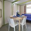 Tavolo da pranzo con sedie bianche, divano blu e vasi di fiori all'interno.