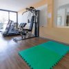 Palestra con attrezzi, tapis roulant e tappetino verde.