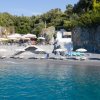 Spiaggia rocciosa con ombrelloni e sedie.