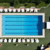 Vista dall'alto di una piscina rettangolare circondata da ombrelloni bianchi.