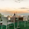 Tavolo apparecchiato al tramonto con sedie bianche e vista panoramica.