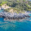 Costa rocciosa con acqua cristallina e vegetazione.