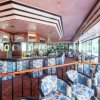 Interno di un bar elegante con sedie fiorite e grandi finestre.
