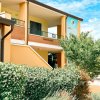 Edificio giallo con balcone e giardino fiorito davanti.