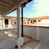 Terrazza coperta con sedie bianche, vista su edifici bianchi e mare.