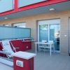 Terrazza con sedie a sdraio e tavolino bianco davanti a un appartamento.