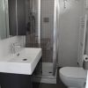 Bagno moderno con doccia, lavabo bianco e WC in una piccola cabina.