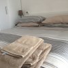 Letto matrimoniale con biancheria a righe e asciugamani beige piegati in primo piano.