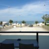 Vista sul mare da un balcone, con auto parcheggiate e cielo blu.