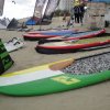 Tavole da surf colorate sulla sabbia con bandiere e tende in spiaggia.