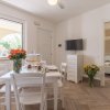 Sala da pranzo luminosa con tavolo bianco e TV a parete.