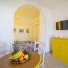 Tavolo rotondo con frutta, mobile giallo e letto colorato.