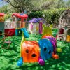 Area giochi all'aperto per bambini con strutture colorate su prato verde.
