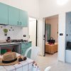 Interno con cucina verde acqua, tavolo apparecchiato, e due camere da letto adiacenti.