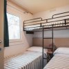 Cameretta con letto a castello e due letti singoli, decorazione semplice e finestra.