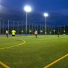 Persone giocano a calcio su un campo illuminato di notte.