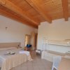 Camera con letto matrimoniale, letti a castello, travi in legno a vista e arredi semplici.