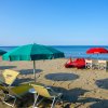 Spiaggia con ombrelloni verdi, sedie a sdraio gialle e canoe rosse.