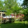 Panchine in un giardino con fiori, alberi e auto parcheggiate.