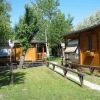 Bungalow di legno con veranda immersi nel verde, sentiero erboso al centro.