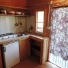 Cucina compatta in legno con lavello, fornello, mini frigo e mensole.