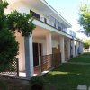 Una casa a due piani con portico, giardino e balcone lungo il primo piano.