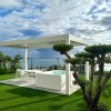 Una terrazza con pergola bianca e vista mare.