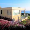 Casa moderna circondata da piante con vista sul mare.