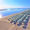 Spiaggia con file ordinate di ombrelloni verdi e bianchi vicino al mare calmo.