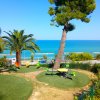 Giardino con altalene, palme e vista mare.
